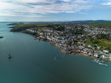Aerial view of the Fowey River estuary with boats historic town buildings and green coastal hills in Fowey Cornwall United Kingdom. Aerial view of the Fowey River estuary with boats historic town buildings and green coastal hills in Fowey Cornwall United Kingdom.