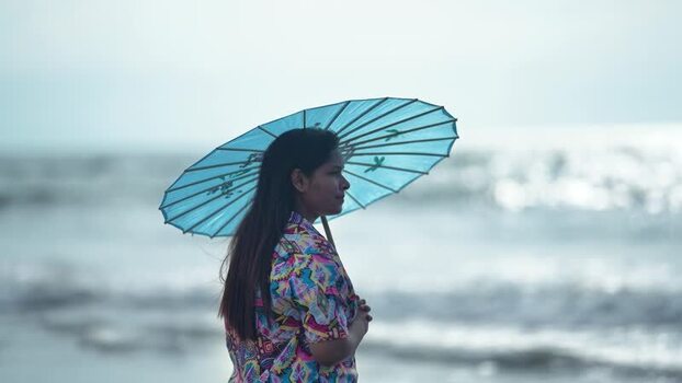 View of a woman with a blue umbrella on the beach Bangladesh. View of a woman with a blue umbrella on the beach Bangladesh.