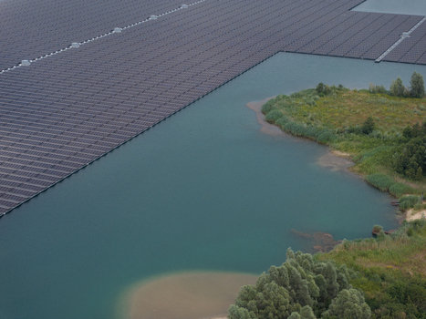 Aerial view of a floating solar farm on a lake with green shoreline and trees in Netherlands. Aerial view of a floating solar farm on a lake with green shoreline and trees in Netherlands.