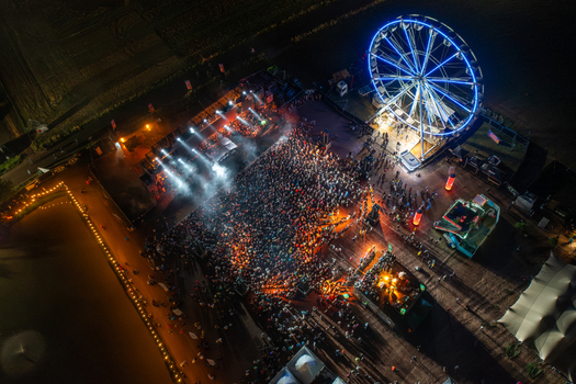 Herzogenaurach Germany 26 July 2025 Aerial view of Open Beatz Festival with a large crowd gathered before a lit stage and a glowing blue Ferris wheel at night.