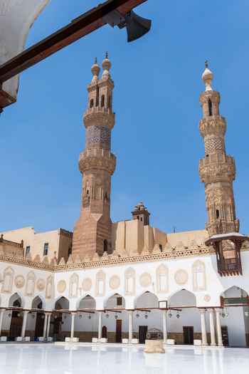 View of the Al Azhar Mosque featuring ornate stone minarets and a white marble courtyard under a clear blue sky in Cairo Egypt. View of the Al Azhar Mosque featuring ornate stone minarets and a white marble courtyard under a clear blue sky in Cairo Egypt.