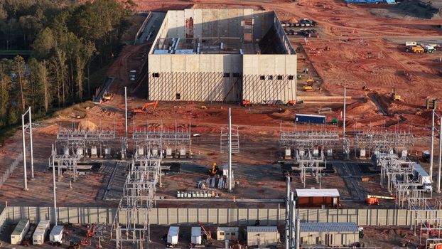 Aerial view of an industrial construction site with a concrete building and electrical substation surrounded by red earth and heavy machinery in Louisa County Virginia United States. Aerial view of an industrial construction site with a concrete building and electrical substation surrounded by red earth and heavy machinery in Louisa County Virginia United States.