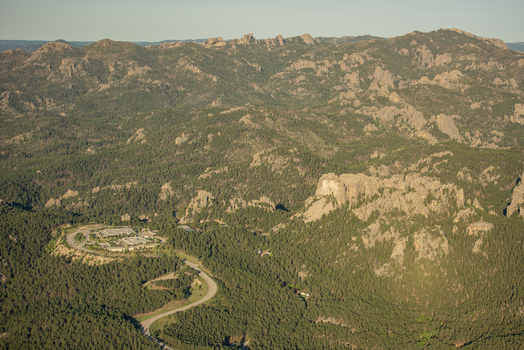 Aerial view of Mount Rushmore National Memorial surrounded by the rugged Black Hills landscape and pine forests in Keystone South Dakota United States. Aerial view of Mount Rushmore National Memorial surrounded by the rugged Black Hills landscape and pine forests in Keystone South Dakota United States.
