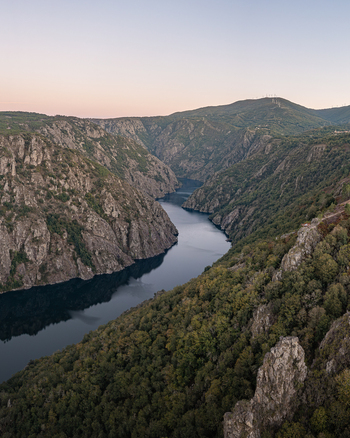 Aerial view of the Sil River canyon in the Ribeira Sacra region with steep rocky cliffs and lush forests at sunset in Lugo Lugo Spain. Aerial view of the Sil River canyon in the Ribeira Sacra region with steep rocky cliffs and lush forests at sunset in Lugo Lugo Spain.