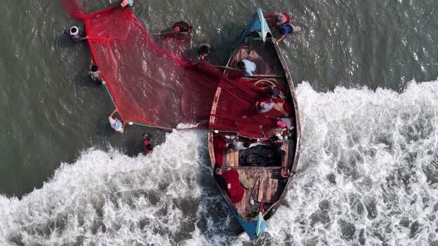 Aerial view of fishermen pulling a red net into a boat Bangladesh. Aerial view of fishermen pulling a red net into a boat Bangladesh.