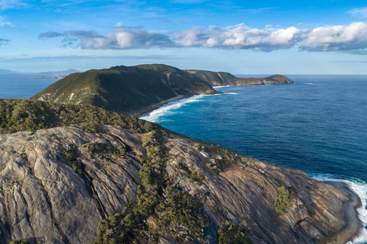 Aerial view of Salmon Holes with rugged granite cliffs turquoise ocean waves crashing against the coastline and lush coastal vegetation in Torndirrup Western Australia Australia.