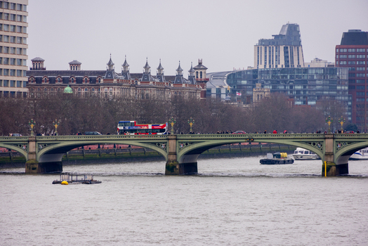 London United Kingdom 12 May 2025 View of Westminster Bridge with a red double decker bus and pedestrians crossing the River Thames under an overcast sky.