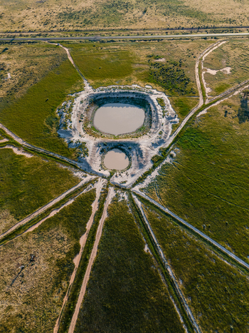 Aerial view of two circular ponds surrounded by a vast flat landscape with dirt tracks converging in the rural fields of Hay New South Wales Australia.
