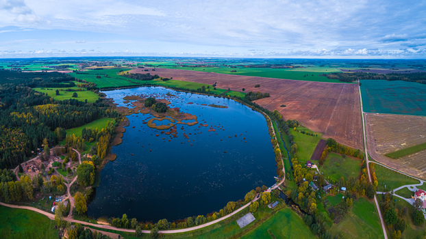 Aerial view of a serene lake surrounded by lush green forests and agricultural fields in the rural landscape of Cesis Cesis Municipality Latvia. Aerial view of a serene lake surrounded by lush green forests and agricultural fields in the rural landscape of Cesis Cesis Municipality Latvia.
