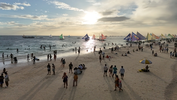 Malay Philippines 02 May 2026 Aerial view of Boracay Island beach at sunset with many tourists and traditional paraw sailboats on the water.
