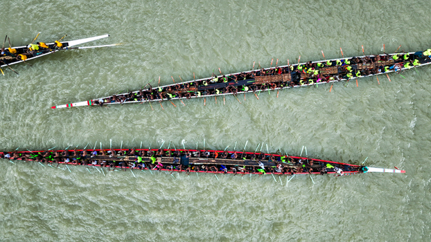 Baghabari Rajshahi Division Bangladesh 20 August 2022 Aerial view of traditional long racing boats filled with many rowers paddling in unison on the river in Baghabari.