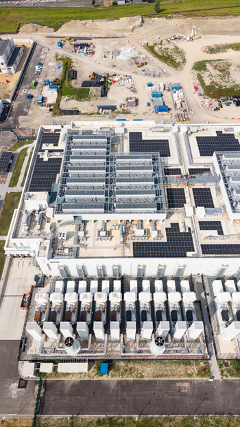 Aerial view of a modern data center campus with rooftop solar panels cooling units and industrial infrastructure in Melegnano Lombardy Italy.