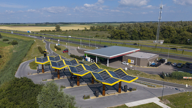 Aerial view of Fastned Charging Station with its distinctive yellow solar canopy located next to a highway in Lelystad Flevoland Netherlands. Aerial view of Fastned Charging Station with its distinctive yellow solar canopy located next to a highway in Lelystad Flevoland Netherlands.
