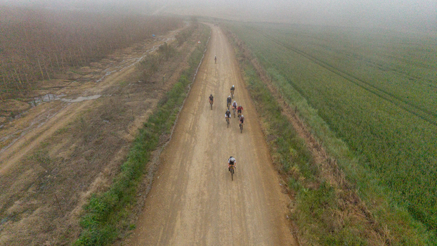 Aerial view of cyclists riding bicycles along a dusty dirt road through the rural landscape of Greyton Western Cape South Africa.