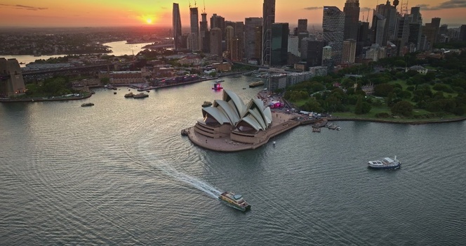 Aerial view of Sydney Opera House at sunset with the city skyline harbour and a ferry crossing the water in Sydney New South Wales Australia. Aerial view of Sydney Opera House at sunset with the city skyline harbour and a ferry crossing the water in Sydney New South Wales Australia.