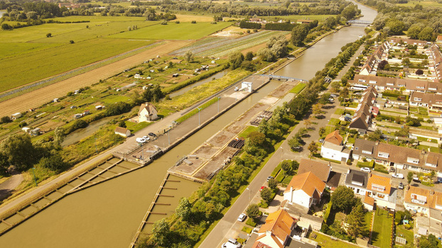 Aerial view of the canal lock in Saint Omer featuring concrete structures adjacent residential housing and surrounding agricultural fields in Saint Omer Hauts de France France. Aerial view of the canal lock in Saint Omer featuring concrete structures adjacent residential housing and surrounding agricultural fields in Saint Omer Hauts de France France.