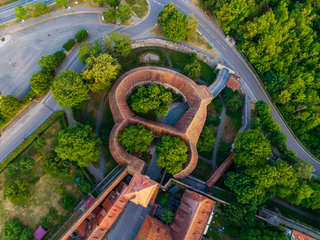 Aerial view of the historic medieval fortifications and stone walls surrounded by lush green trees and terracotta rooftops in Rothenburg ob der Tauber Bavaria Germany. Aerial view of the historic medieval fortifications and stone walls surrounded by lush green trees and terracotta rooftops in Rothenburg ob der Tauber Bavaria Germany.