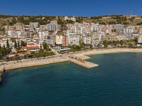 Aerial view of the coastal town of Saranda with its waterfront promenade pier and buildings along the Ionian Sea in Saranda Vlore County Albania. Aerial view of the coastal town of Saranda with its waterfront promenade pier and buildings along the Ionian Sea in Saranda Vlore County Albania.