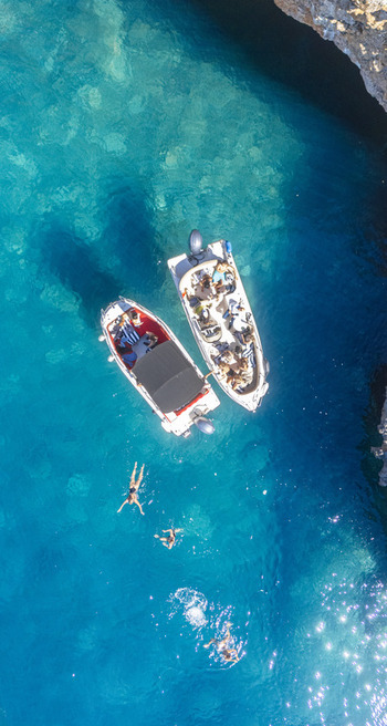 Aerial view of two motorboats anchored in clear turquoise water with people swimming nearby in Tivat Tivat Municipality Montenegro. Aerial view of two motorboats anchored in clear turquoise water with people swimming nearby in Tivat Tivat Municipality Montenegro.