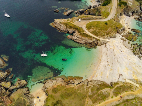 Aerial view of Pointe des Poulains with its rugged coastline turquoise waters sandy beach and small boats in Sauzon Bretagne France. Aerial view of Pointe des Poulains with its rugged coastline turquoise waters sandy beach and small boats in Sauzon Bretagne France.