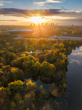 Aerial view of the Warsaw skyline at sunset with the National Stadium and autumn foliage in Skaryszewski Park by the lake in Poland. Aerial view of the Warsaw skyline at sunset with the National Stadium and autumn foliage in Skaryszewski Park by the lake in Poland.