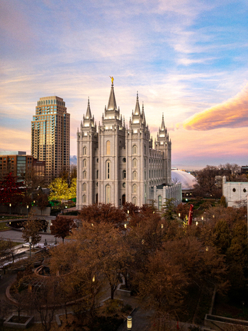 Salt Lake City Utah United States 19 November 2019 Aerial view of Salt Lake Utah Temple surrounded by autumn trees and city buildings under a soft sunset sky.