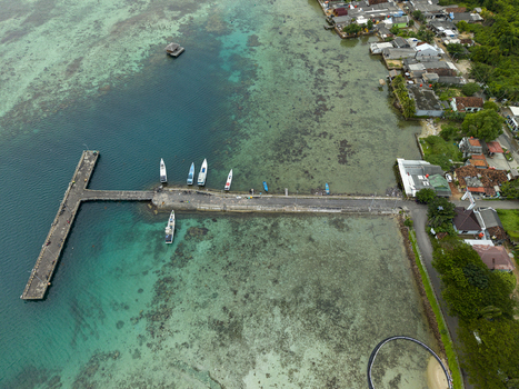Aerial view of boats docked at the pier as turquoise waters meet the shore contrasting with the dense greenery and buildings Karimunjawa Jawa Tengah Indonesia. Aerial view of boats docked at the pier as turquoise waters meet the shore contrasting with the dense greenery and buildings Karimunjawa Jawa Tengah Indonesia.