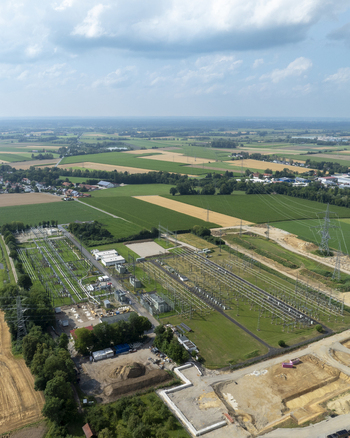 Aerial view of the Neufinsing electrical substation surrounded by green agricultural fields and power lines in Finsing Bayern Germany.