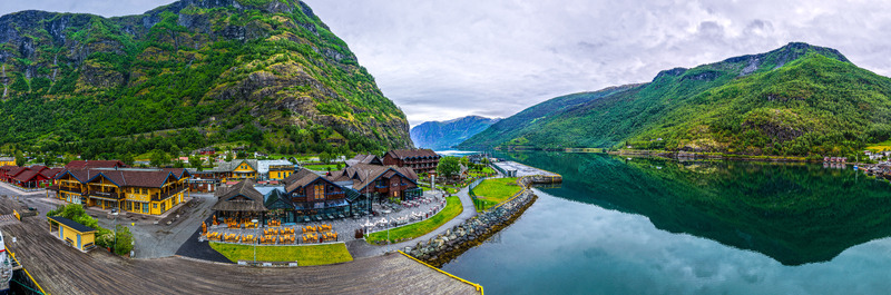 Flam Norway 18 June 2026 Aerial view of the village of Flam nestled between steep green mountains and the calm waters of the Aurlandsfjord featuring traditional wooden buildings and a scenic waterfront. Flam Norway 18 June 2026 Aerial view of the village of Flam nestled between steep green mountains and the calm waters of the Aurlandsfjord featuring traditional wooden buildings and a scenic waterfront.