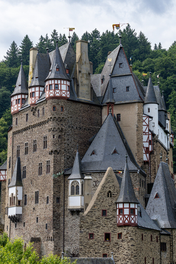 View of the medieval Eltz Castle with its iconic stone towers and timber framed architecture nestled against a lush green forest in Wierschem Rhineland Palatinate Germany.