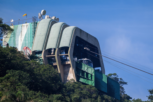 Aerial view of the Sugarloaf Mountain cable car station with its distinctive curved concrete architecture nestled among lush green trees in Rio de Janeiro Rio de Janeiro Brazil.