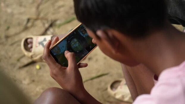 View of a boy playing a mobile game on a smartphone Bangladesh. View of a boy playing a mobile game on a smartphone Bangladesh.