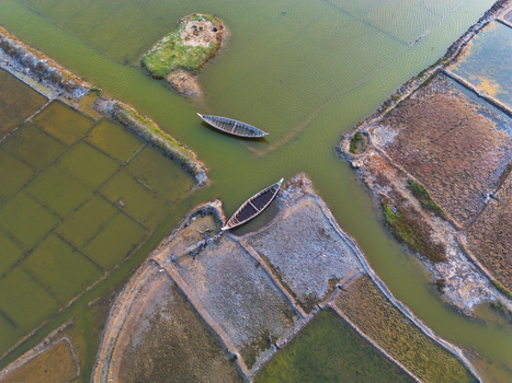 Aerial view of traditional wooden boats floating in geometric salt pans and aquaculture ponds under soft light in Moheskhali Upazila Chittagong Division Bangladesh. Aerial view of traditional wooden boats floating in geometric salt pans and aquaculture ponds under soft light in Moheskhali Upazila Chittagong Division Bangladesh.