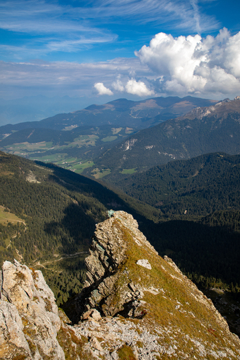 View of the Dolomites mountains featuring jagged rocky peaks dense green forests in the valley and distant mountain ranges under a blue sky with white clouds Rocca Pietore Veneto Italy. View of the Dolomites mountains featuring jagged rocky peaks dense green forests in the valley and distant mountain ranges under a blue sky with white clouds Rocca Pietore Veneto Italy.