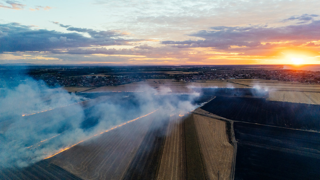 Aerial view of a field fire burning in agricultural land at sunset with smoke rising over the landscape near Sremska Mitrovica Vojvodina Serbia. Aerial view of a field fire burning in agricultural land at sunset with smoke rising over the landscape near Sremska Mitrovica Vojvodina Serbia.