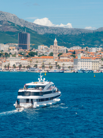Aerial view of a large white yacht cruising on the blue Adriatic Sea with the historic old town and Saint Domnius Cathedral in Split Split Dalmatia County Croatia. Aerial view of a large white yacht cruising on the blue Adriatic Sea with the historic old town and Saint Domnius Cathedral in Split Split Dalmatia County Croatia.