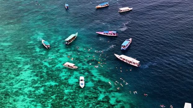 Aerial view of boats and swimmers in clear water Indonesia.