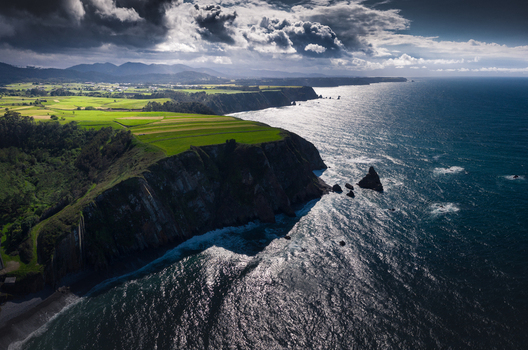 Aerial view of the rugged cliffs and lush green fields of Gaztelugatxe under a dramatic stormy sky in Gaztelugatxeko Doniene Basque Country Spain. Aerial view of the rugged cliffs and lush green fields of Gaztelugatxe under a dramatic stormy sky in Gaztelugatxeko Doniene Basque Country Spain.