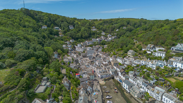 Aerial view of the historic coastal village of Polperro nestled in a lush green valley with traditional stone cottages and small boats moored in the harbor Polperro Cornwall United Kingdom. Aerial view of the historic coastal village of Polperro nestled in a lush green valley with traditional stone cottages and small boats moored in the harbor Polperro Cornwall United Kingdom.