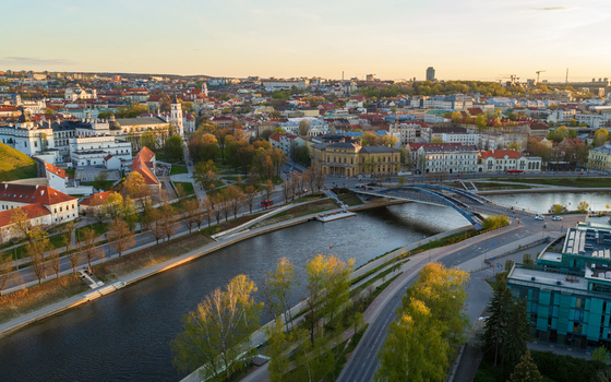Aerial view of the Vilnius city skyline and Neris River featuring the Mindaugas Bridge historic architecture and lush green trees during a golden sunset Vilnius County Lithuania. Aerial view of the Vilnius city skyline and Neris River featuring the Mindaugas Bridge historic architecture and lush green trees during a golden sunset Vilnius County Lithuania.