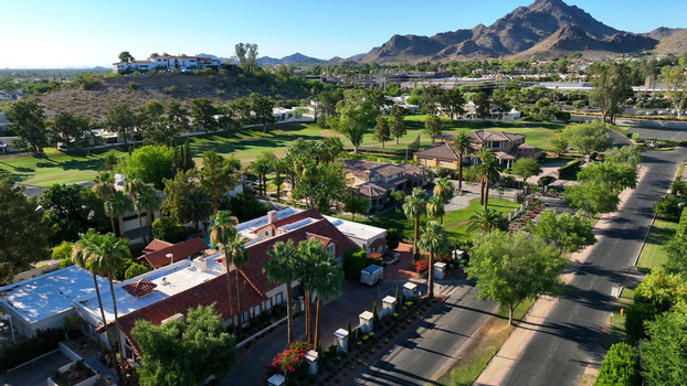 Aerial view of a residential neighborhood with palm trees and houses with red tiled roofs near a golf course in Phoenix Arizona United States.