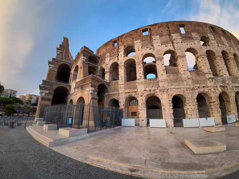 View of the Colosseum an iconic ancient amphitheater with weathered stone arches and tiered levels under a clear blue sky in Roma Lazio Italy.