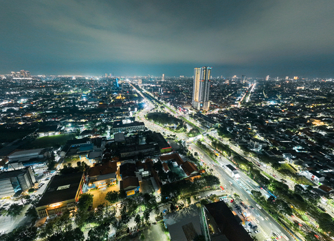 Aerial view of the illuminated cityscape of Surabaya at night featuring dense urban development glowing street lights and a high rise building in Surabaya East Java Indonesia. Aerial view of the illuminated cityscape of Surabaya at night featuring dense urban development glowing street lights and a high rise building in Surabaya East Java Indonesia.