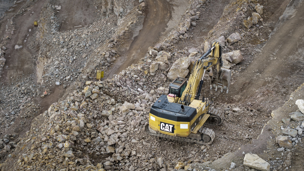 Aerial view of a yellow Caterpillar excavator working in the kopalnia porfiru i diabazu quarry surrounded by rocky terrain and dirt paths in Krakow Lesser Poland Voivode Poland. Aerial view of a yellow Caterpillar excavator working in the kopalnia porfiru i diabazu quarry surrounded by rocky terrain and dirt paths in Krakow Lesser Poland Voivode Poland.