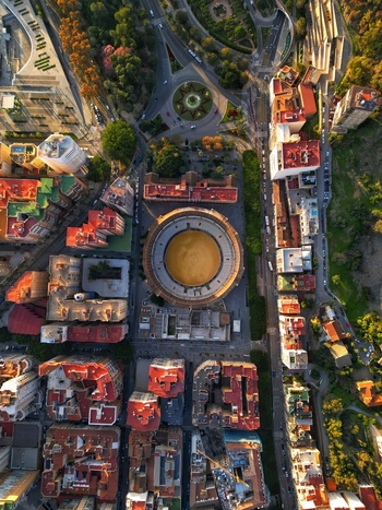 Aerial view of the Plaza de toros de La Malagueta bullring surrounded by urban buildings and lush trees during sunset in Malaga Andalusia Spain. Aerial view of the Plaza de toros de La Malagueta bullring surrounded by urban buildings and lush trees during sunset in Malaga Andalusia Spain.
