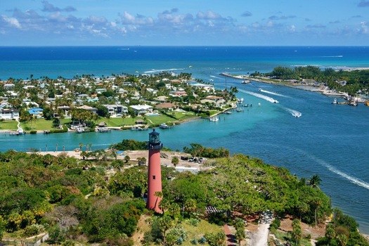 Aerial view of the red Jupiter Inlet Lighthouse overlooking the turquoise waters of the inlet with boats and coastal homes in Jupiter Florida United States. Aerial view of the red Jupiter Inlet Lighthouse overlooking the turquoise waters of the inlet with boats and coastal homes in Jupiter Florida United States.