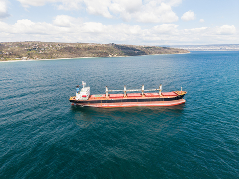 Aerial view of a large cargo ship anchored in the blue waters near Fichoza Beach Veteran with coastal hills under a cloudy sky Varna Varna Bulgaria. Aerial view of a large cargo ship anchored in the blue waters near Fichoza Beach Veteran with coastal hills under a cloudy sky Varna Varna Bulgaria.