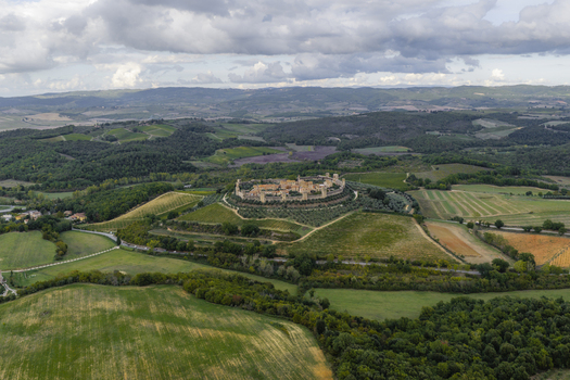 Aerial view of the historic walled town of Monteriggioni surrounded by olive groves vineyards and rolling hills in the Tuscan countryside Monteriggioni Tuscany Italy.