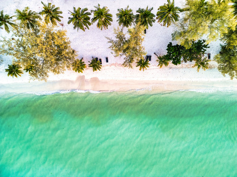 Aerial view of the white sandy beach meeting the turquoise waters fringed by palm trees casting shadows on the sand Preah Sihanouk Sihanoukville Cambodia.