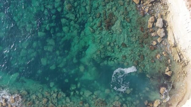 Aerial view of turquoise coastal waters and rocky shore Cyprus.